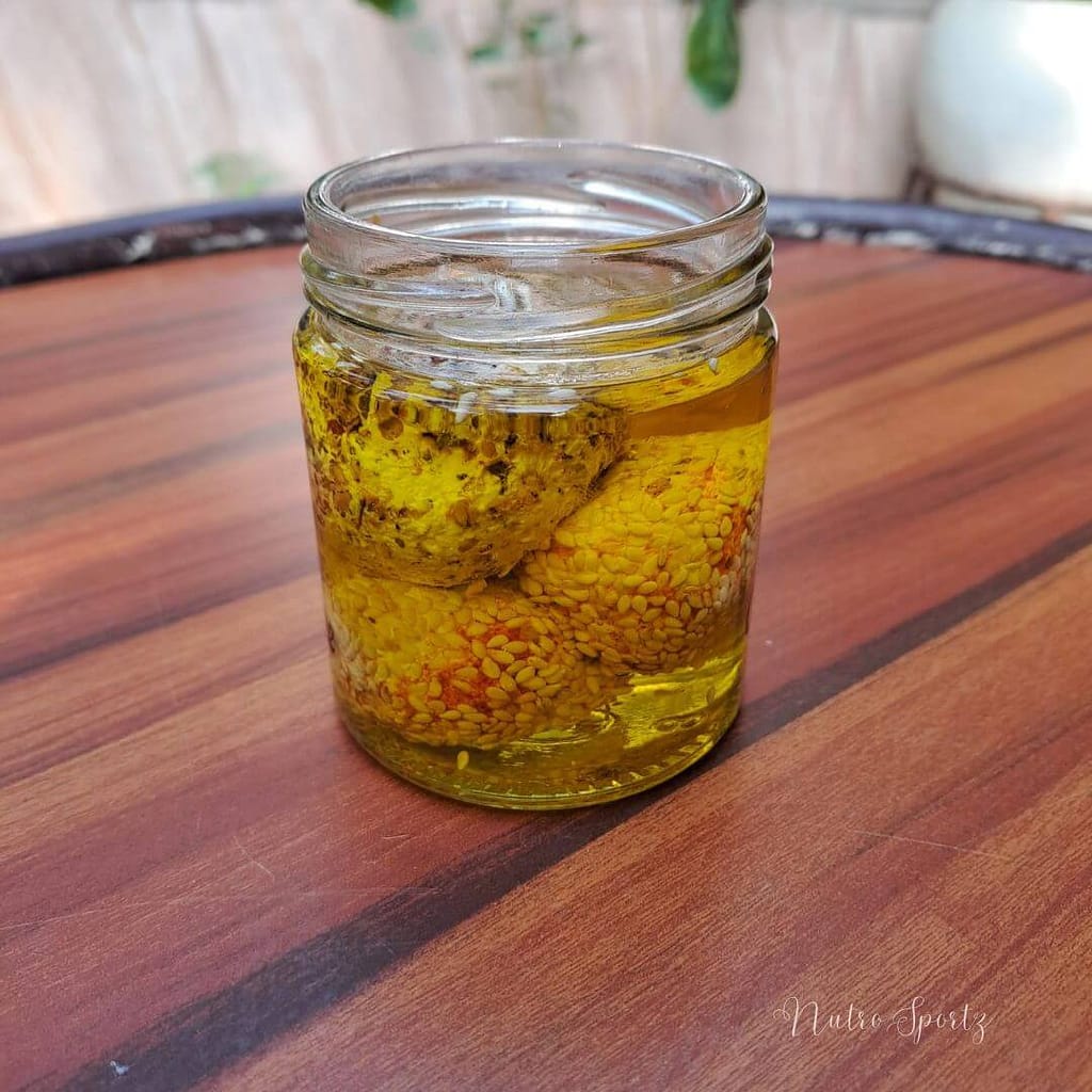 An image of labneh balls immersed in olive oil in a jar.