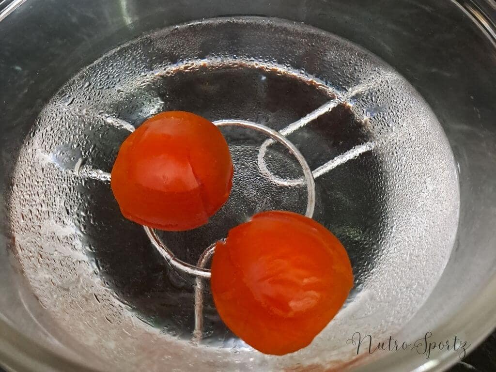An image of tomatoes dipped in a bowl filled with chilled water.